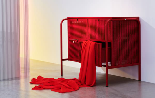 Commode quatre tiroirs en métal rouge. Un tissu rouge semble jaillir de l'un des tiroirs.
