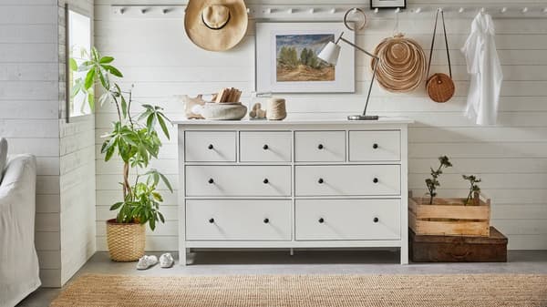 Cómoda HEMNES blanca de 8 cajones, con una lámpara, velas y artículos decorativos en su superficie.