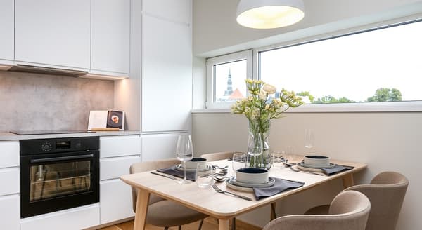 Compact dining area in white kitchen with flowers on the table and window view.