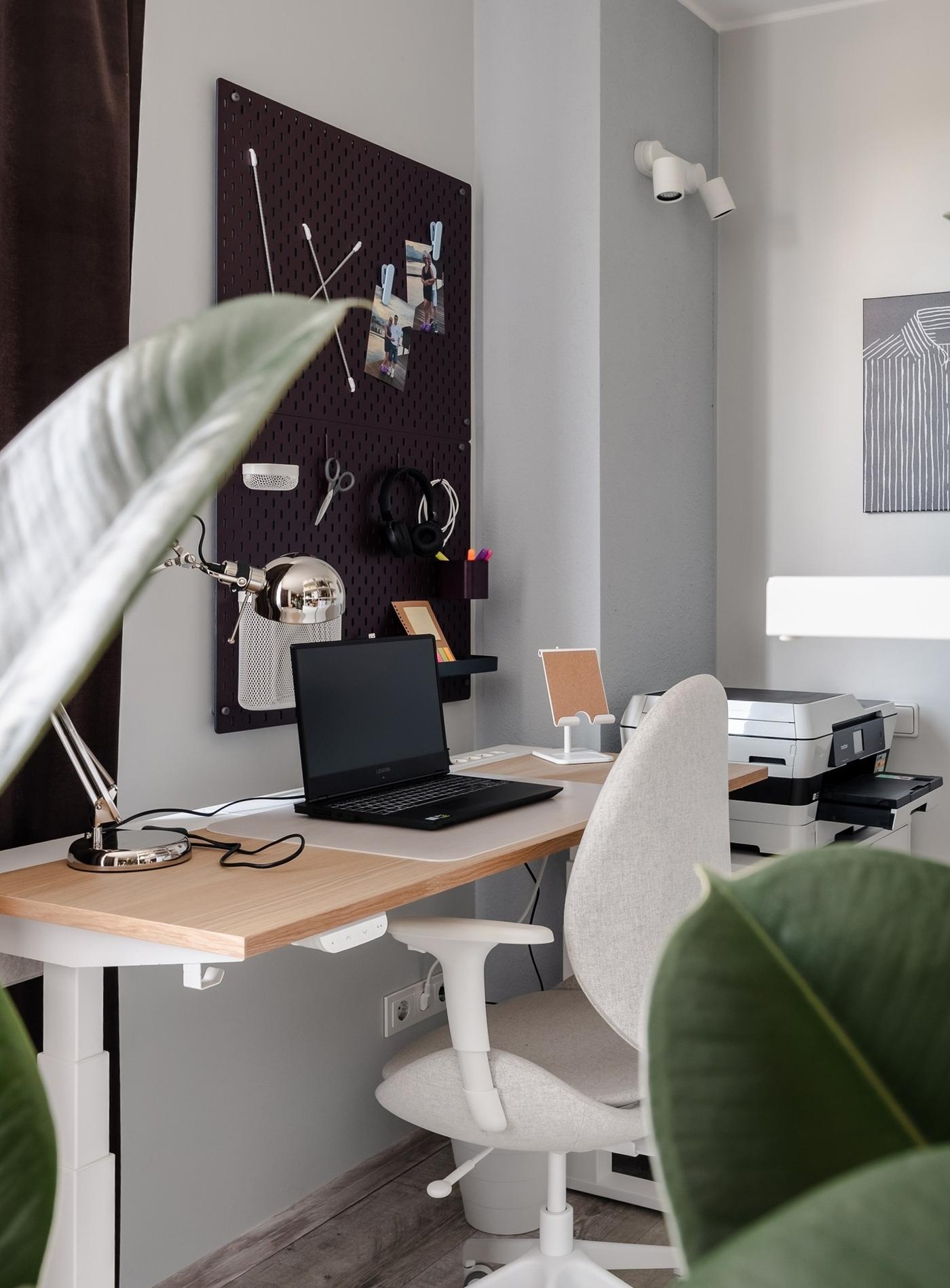 Compact home workspace with a desk, office chair, wall organiser and task lighting.