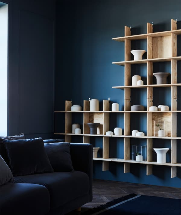 Contrastant avec le mur foncé, l’étagère en bois clair garnie d’objets rigoureusement choisis dégage une impression d’apaisement. Les objets en céramique servent à la fois à décorer et à ranger.