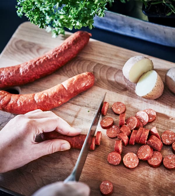 Cooked diced potatoes and vegetables in a pan are being tipped into a white bowl.