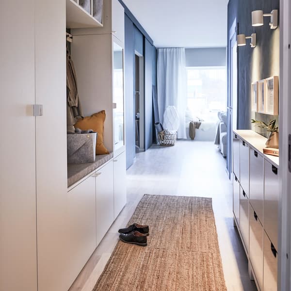 Couloir étroit menant à un séjour, avec des unités de rangement IKEA PLATSA sur chaque mur.