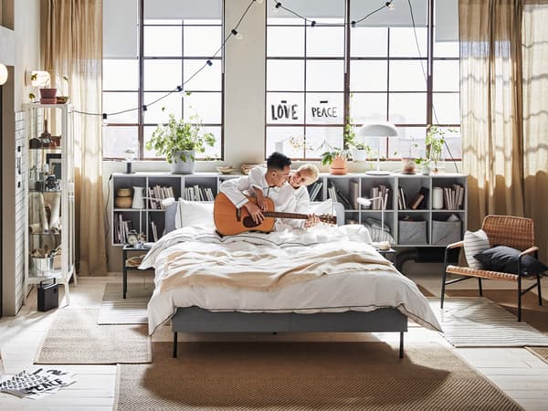 Couple happily plays an instrument in the bedroom.