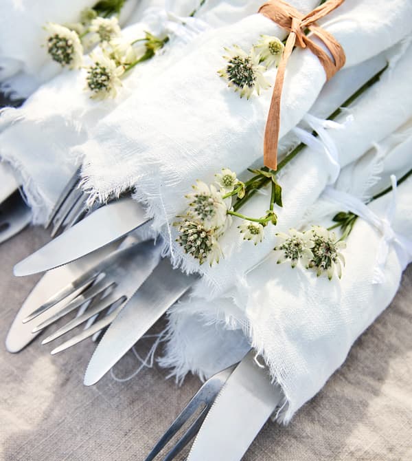 Couverts enveloppés dans un tissu blanc et noués avec de la ficelle.