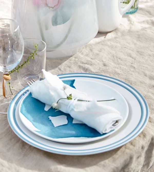 Couverts enveloppés dans un tissu blanc et noués avec un ruban, posés sur une assiette.