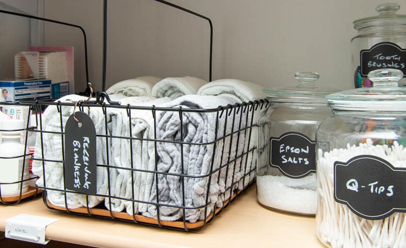 Couvertures à langer et trousse de toilette pour bébé dans des corbeilles en fil avec poignée PLEJA noires.