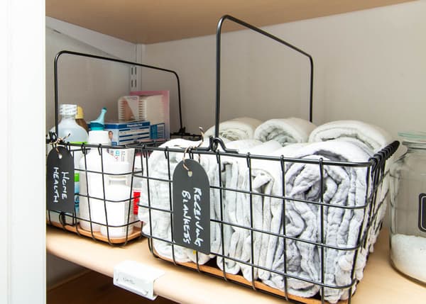 Couvertures à langer et trousse de toilette pour bébé dans des corbeilles en fil avec poignée PLEJA noires.