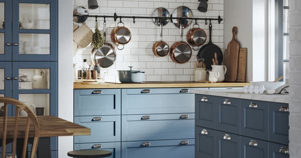 Cozy kitchen with LERHYTTAN blue cabinets, hanging cookware, wooden counters, and neatly arranged dishes and cooking essentials.