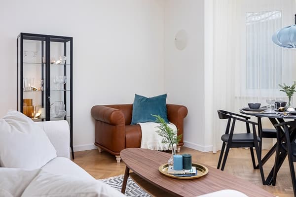 Cozy reading corner with leather armchair, glass cabinet, and teal cushion