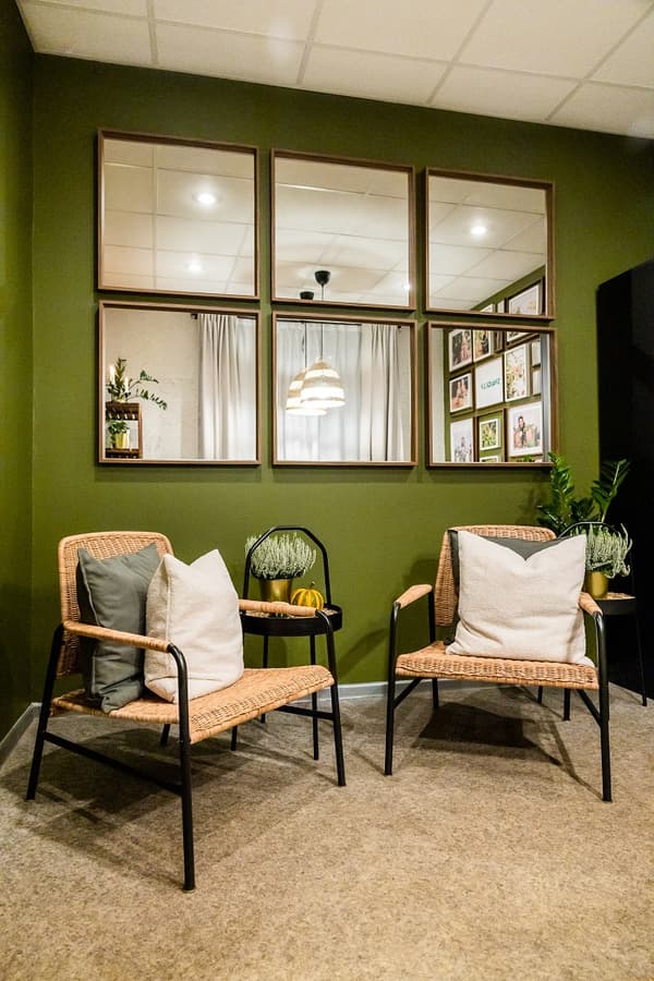 Cozy seating corner with rattan chairs, green wall, and decorative mirrors