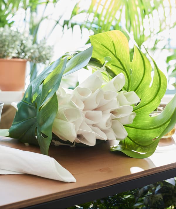 Créez un joli centre de table avec un mélange de plantes vertes. Cachez les serviettes dans quelques jolies feuilles qui ne sècheront jamais, comme la feuille artificielle IKEA SMYCKA!