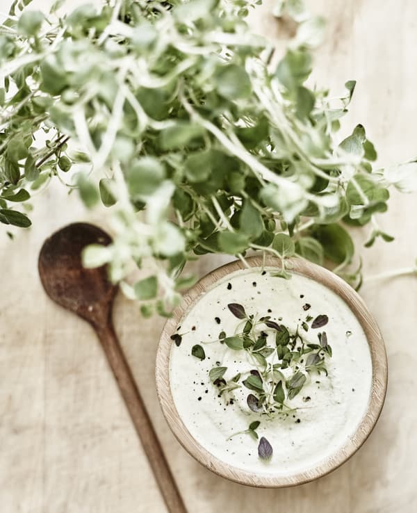 Crème de noix de cajou garnie de thym et servie dans un bol en bois.