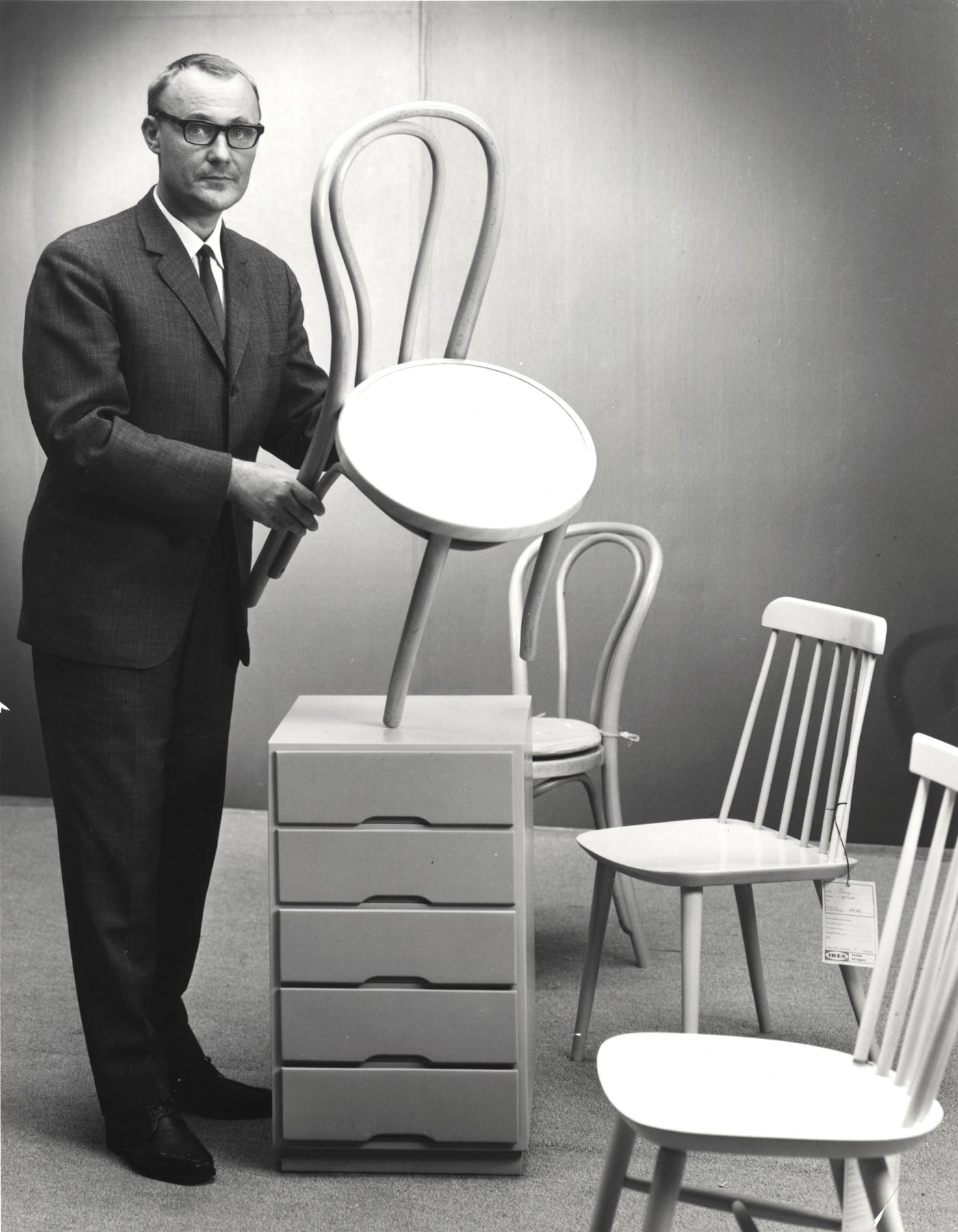 Črno-bela fotografija mladega Ingvarja Kamprada, ki v studiu drži stol podjetja IKEA.