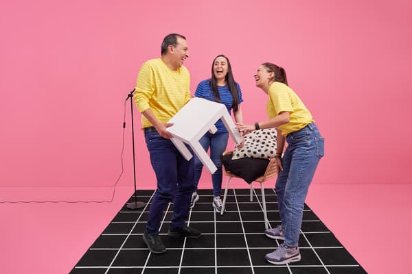 Cuatro colaboradores con sus poleras azules y amarillas jugando con sillas.