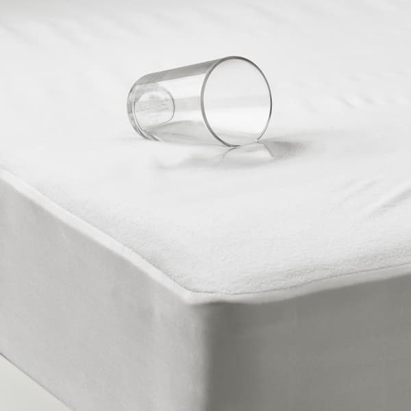 Cubre colchón impermeable con un vaso de agua vertido sobre.