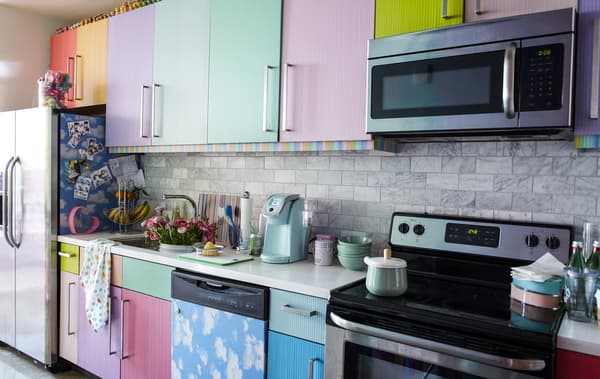 Cuisine avec portes multicolores et plan de travail blanc.