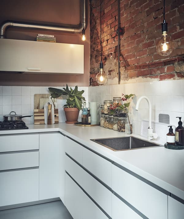 Cuisine blanche avec mur en briques apparentes.