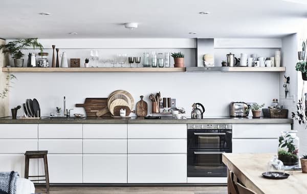 Cuisine blanche avec plans de travail en béton et tablettes.
