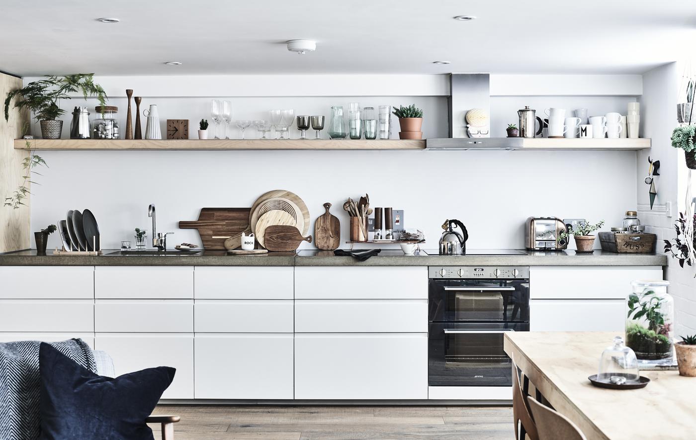 Cuisine blanche avec plans de travail en béton et tablettes.