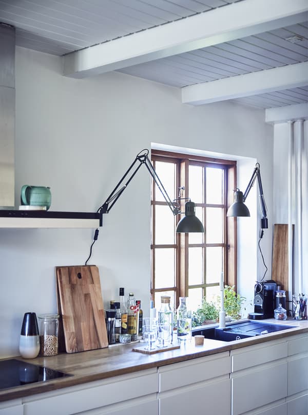 Cuisine blanche avec plans de travail et lampes.