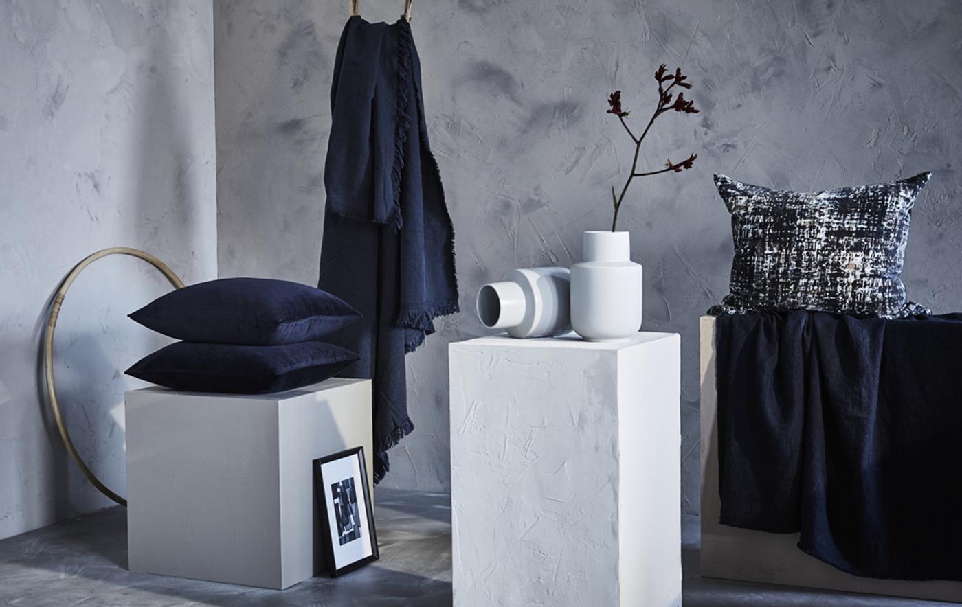 Cuscini e plaid blu in una stanza nelle tonalità del grigio e del bianco - IKEA