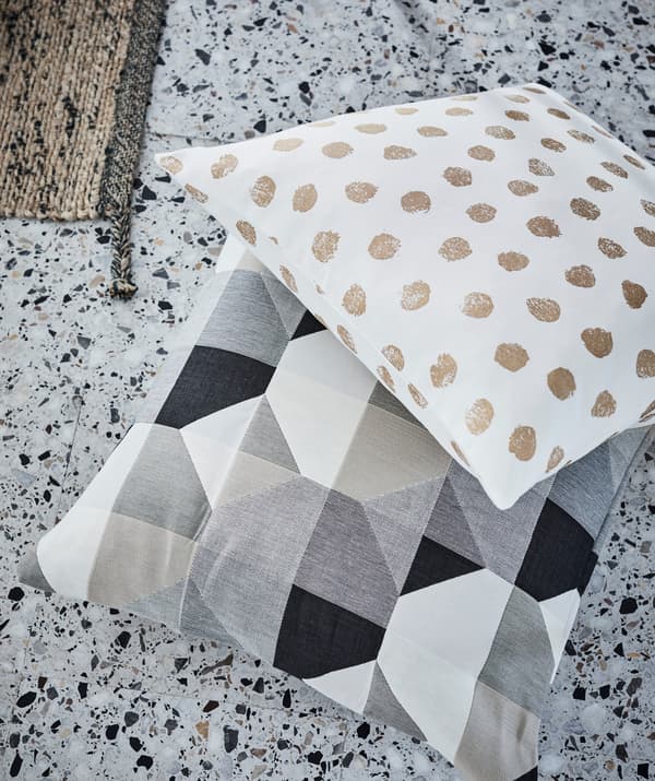 Cushions with simplistic, strong dot and block patterns laying on terrazzo floor tiles.