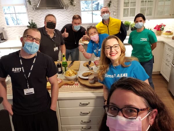 Dans le cadre de l’atelier Recevez pour les Fêtes, l’équipe de IKEA Ville de Québec se tient autour d’un îlot de cuisine gris pâle et blanc et sourit à la caméra.