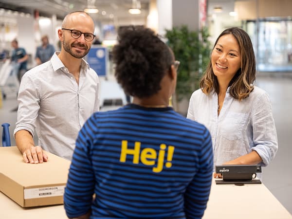 Dans un magasin IKEA, deux personnes retournent un article IKEA au comptoir des retours.