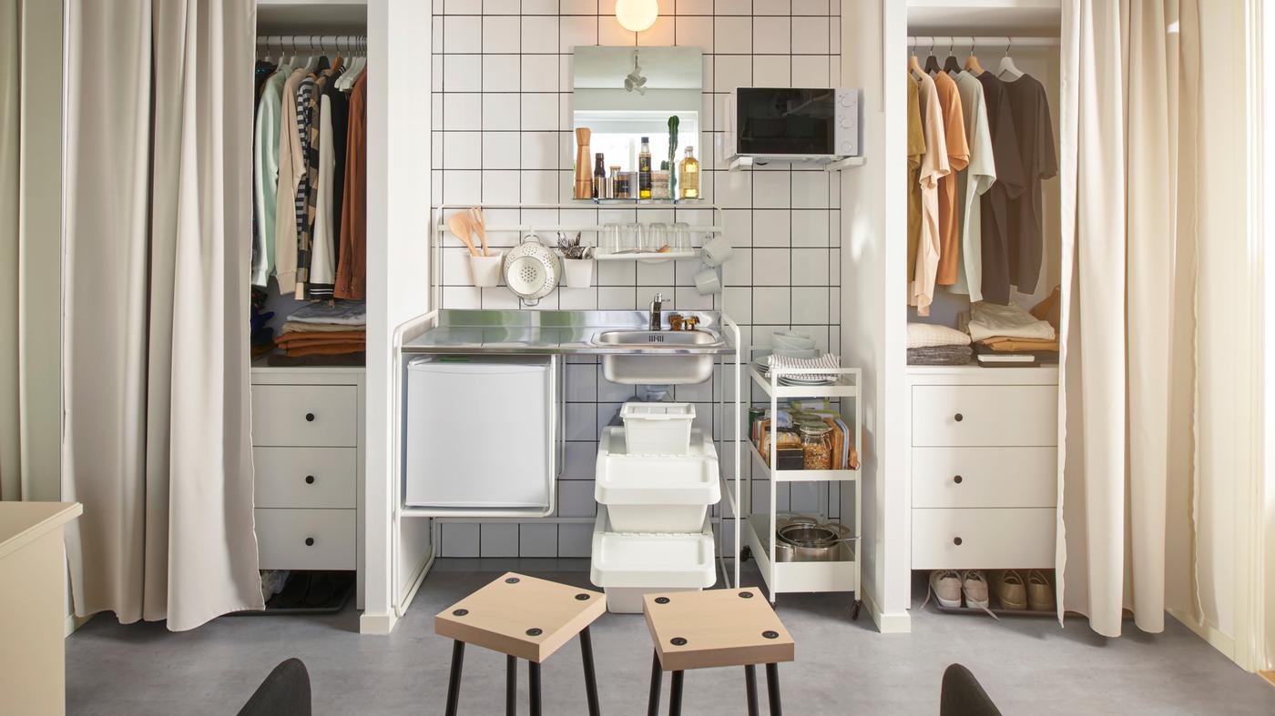 Dans une chambre d’étudiant partagée, mini‑cuisine SUNNERSTA installée entre deux rangements. Rideaux suspendus devant les rangements.