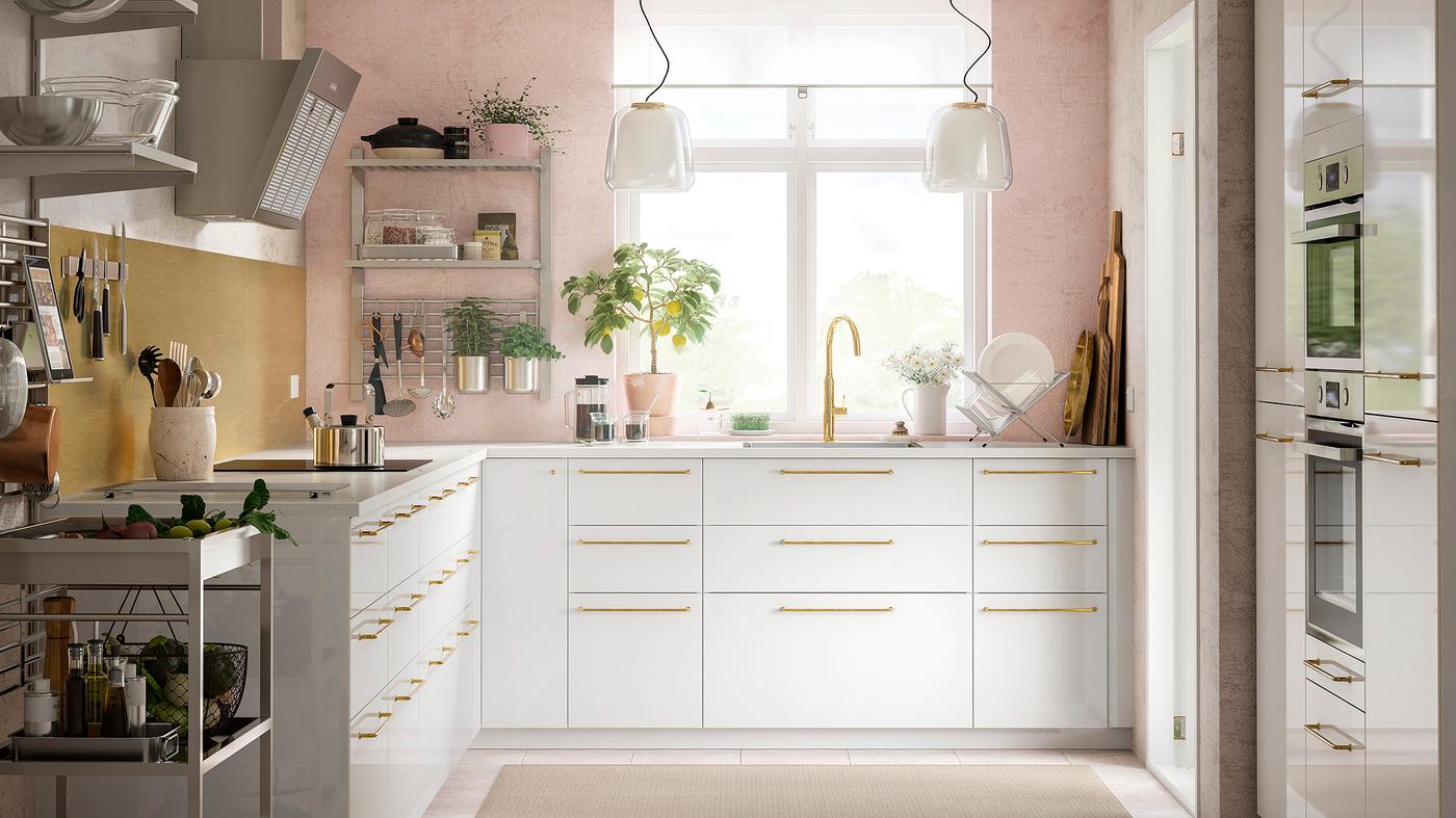 Dapur dengan dinding berwarna merah jambu mempunyai rak dinding yang menampung perkakas dapur selain laci dan kabinet berwarna putih dengan perincian berwarna loyang.