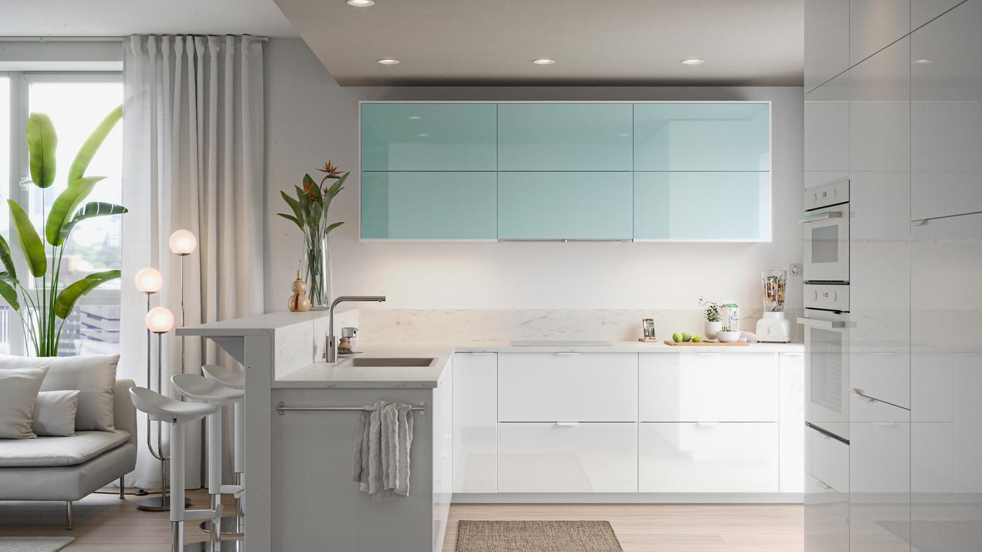 Dapur minimalis dengan pintu berkilat berwarna putih dan firus, landas cencang dengan buah-buahan, pengisar berisi buah-buahan.