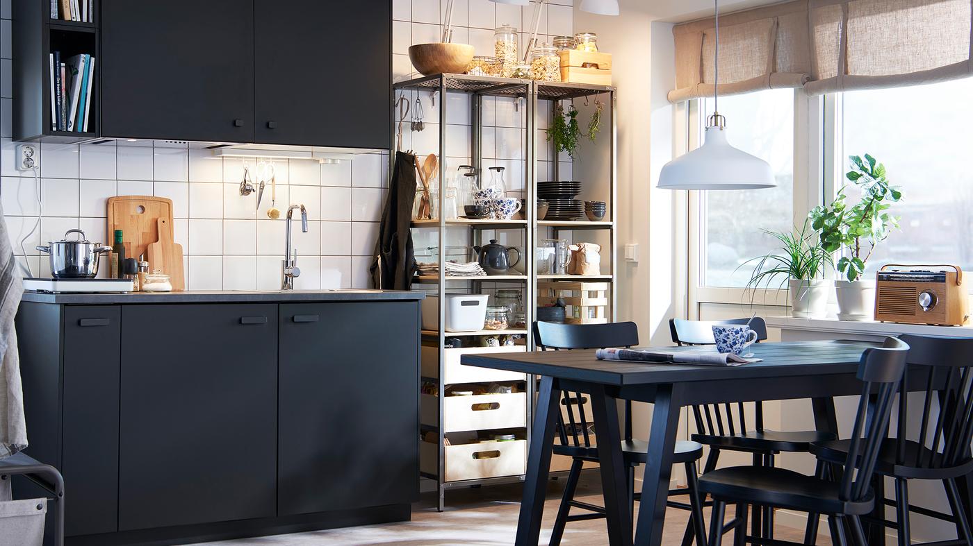 Dapur monokrom yang anggun dengan kabinet berwarna antrasit, meja dan kerusi berwarna hitam serta rak logam terbuka.