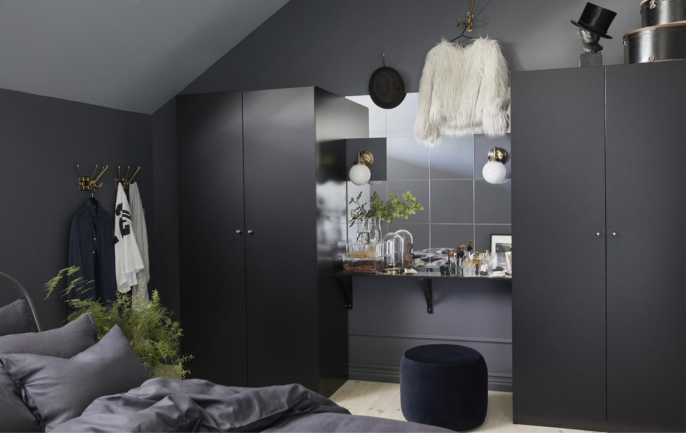 Dark bedroom furniture can make the room feel spacious, too. Try putting a wall of mirrors and a vanity table between two black-brown PAX wardrobes. The wardrobes from IKEA have black doors and lots of room inside to get organised.