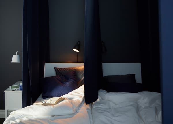 Dark curtains hang at the sides and down the middle of this bed to make it possible to create separate sleeping zones.