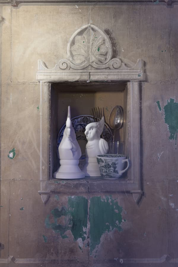 De la vaisselle et deux oiseaux blancs décoratifs nichés dans le mur.