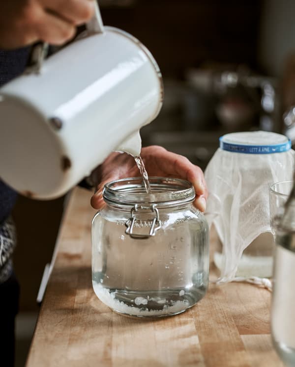De l’eau versée d’une cruche en émail dans un bocal en verre de style Kilner.