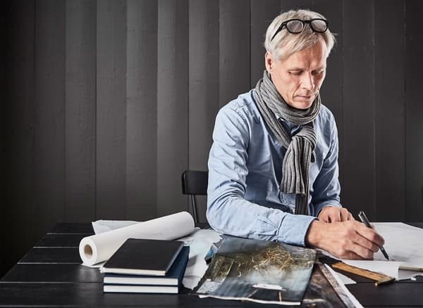 Décorateur d’intérieur assis à une table, en train de feuilleter des magazines et de faire des esquisses pour sa cuisine de rêve.