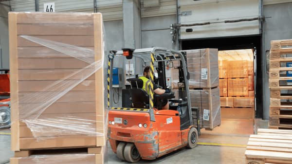 倉庫でイケアのコワーカーがフォークリフトを運転して荷物を運んでいる