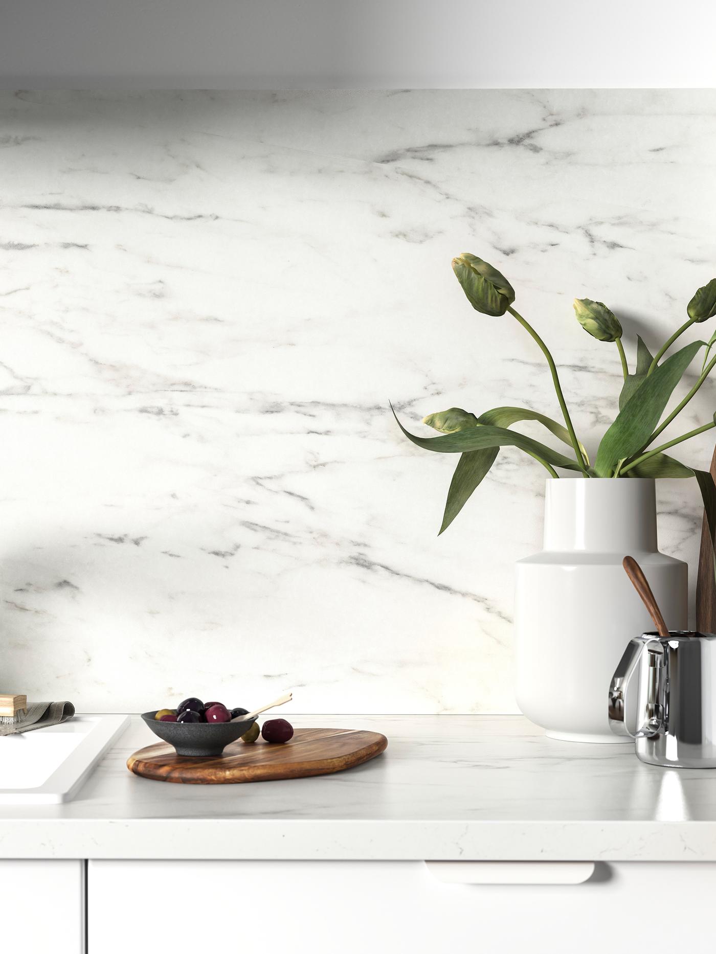 Der weisse Spritzschutz und die weisse marmorierte Arbeitsplatte harmonisieren bestens miteinander. Auf der Platte steht eine weisse Vase mit Blumen.