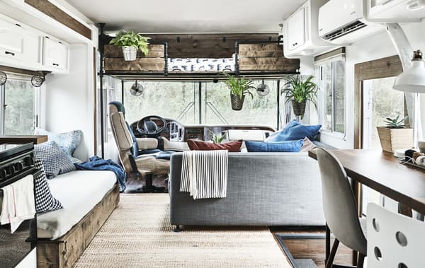 Derrière le volant d’un mobil-home, coin cuisine et séjour décoré de plantes.