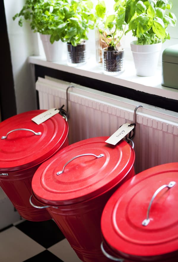 Des bacs métalliques rouges sont suspendus au radiateur pour créer une zone de recyclage intéressante et attrayante.