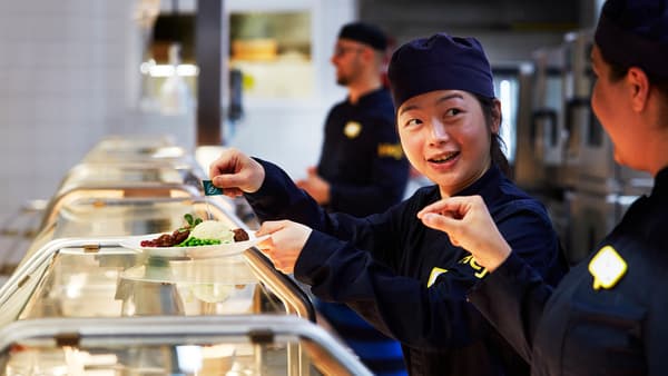 Des collaborateurs IKEA portant des uniformes bleu foncé qui préparent des assiettes dans le restaurant.