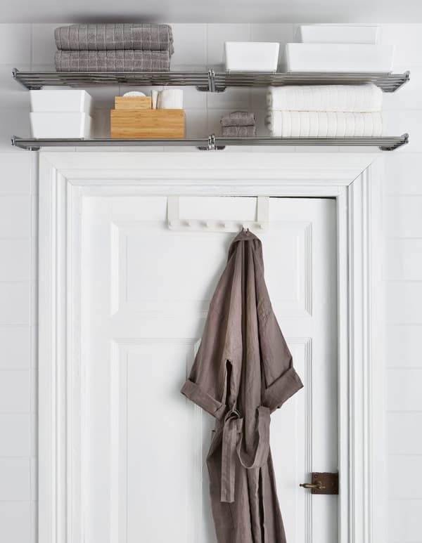 Des étagères en métal installées au-dessus de la porte accueillent serviettes et accessoires, alors que la patère pour porte reçoit un peignoir.