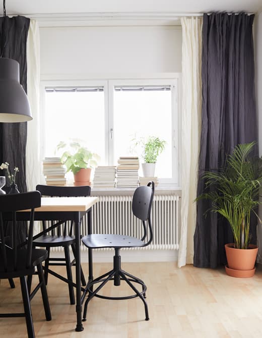 Des rideaux blancs et bleus superposés pendent du plafond jusqu’au sol et de mur à mur, dans une salle à manger.