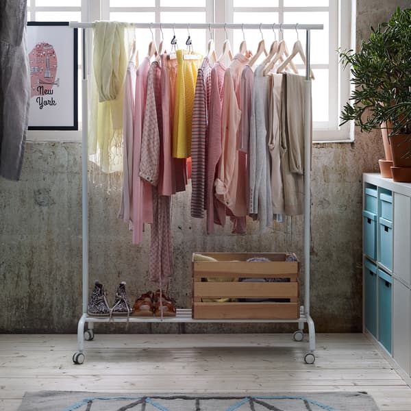 Des vêtements couleurs pastel suspendus à un portant RIGGA dans une pièce baignée de lumière.