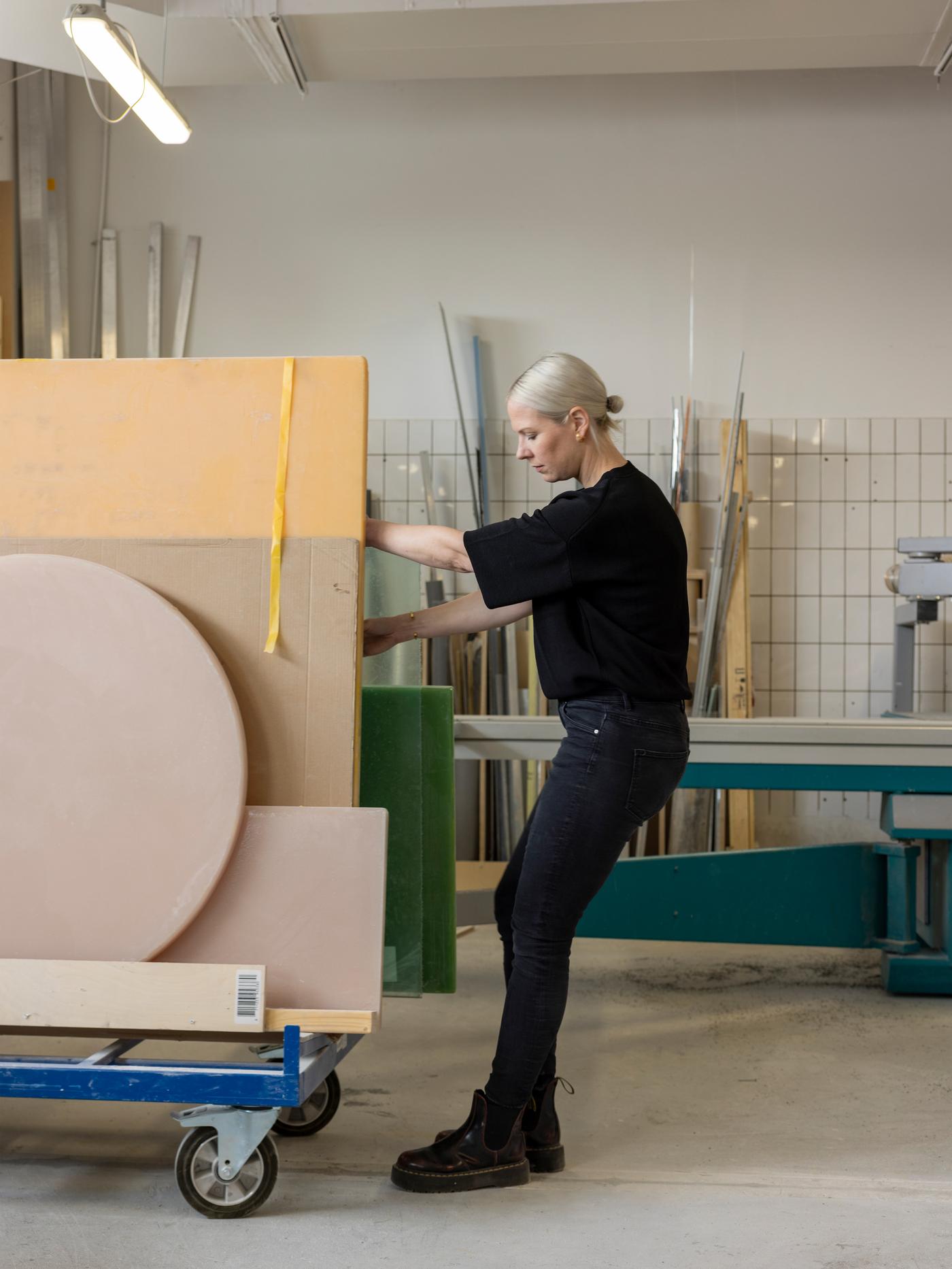 Designer Sabine Marcelis, dressed in black, pulls a trolley with sheets of resin and cardboard in her Rotterdam workshop.