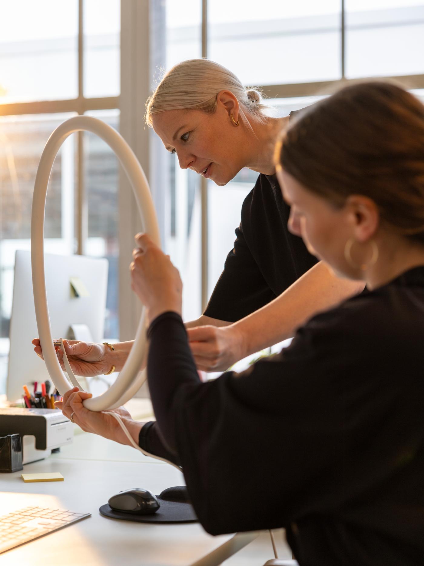 Designer Sabine Marcelis inspects a prototype of a VARMBLIXT circular wall lamp with her assistant in her Rotterdam studio.