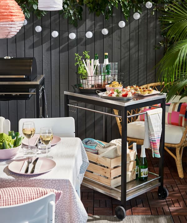 Desserte IKEA KLASEN en acier inoxydable avec des aliments et des boissons dans une zone de barbecue.