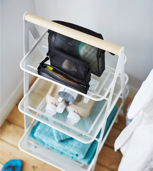 Desserte IKEA RISATORPP avec des choses essentielles pour la toilette telles que serviettes, shampooing et savon.